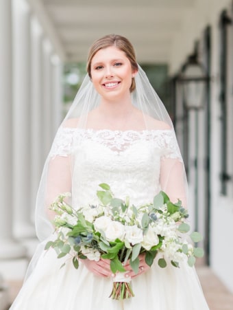 A bride in a white wedding dress with an off-the-shoulder veil, looking elegant and radiant on her special day.