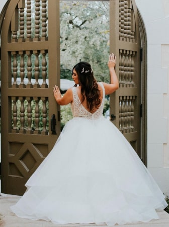 A bride in a wedding dress standing in front of an open door, ready to embark on her new journey.